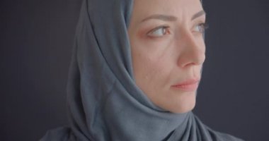 Türbanlı genç çekici Müslüman kadının gri üzerine izole edilmiş arka planlı kameraya bakan yakın çekim portresi