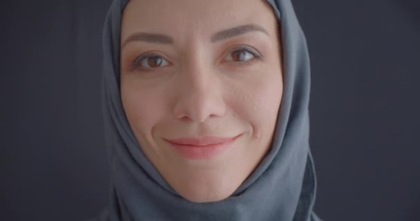 Retrato de cerca de una joven atractiva mujer musulmana en hijab mirando a la cámara sonriendo felizmente con un fondo aislado en gris — Vídeo de stock