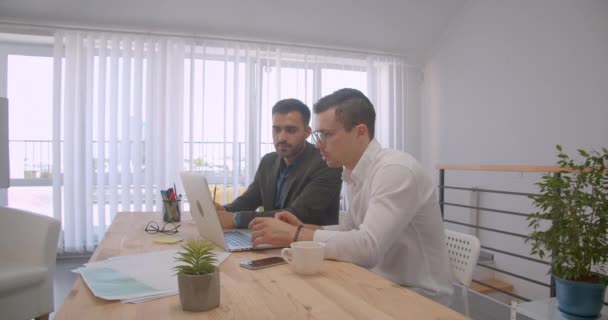 Retrato de dos adultos exitosos hombres de negocios usando el portátil y teniendo una discusión en la oficina en el interior — Vídeos de Stock