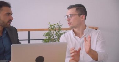 İki başarılı işadamının kapalı ofiste dizüstü bilgisayarda bir projeyi tartıştığı closeup portresi