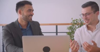 İki çekici işadamının kapalı ofiste dizüstü bilgisayarda bir projeyi tartıştığı closeup portresi