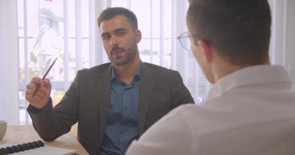 Κοντινό πορτρέτο δύο Καυκάσιων επιχειρηματιών που έχουν μια επίσημη συζήτηση στο γραφείο σε εσωτερικούς χώρους — Αρχείο Βίντεο