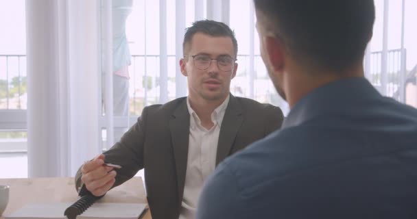 Primo piano ritratto di uomini d'affari attraenti in occhiali che hanno un colloquio di lavoro in ufficio al chiuso sul posto di lavoro — Video Stock