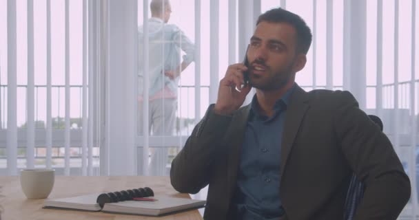 Retrato de close-up de empresário atraente ter um telefonema falando no escritório dentro de casa no local de trabalho — Vídeo de Stock