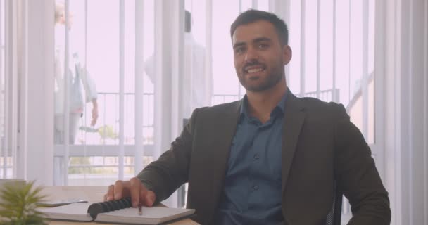 Primo piano ritratto di uomo d'affari attraente guardando la fotocamera sorridente felicemente in ufficio al chiuso sul posto di lavoro — Video Stock