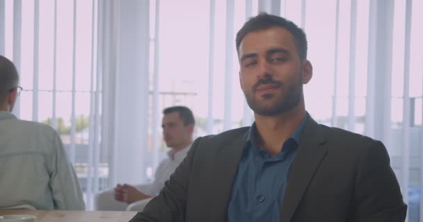 職場の屋内で陽気に笑顔のカメラを見ている自信のある白人ビジネスマンのクローズアップポートレート — ストック動画