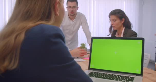 Porträt von vier Kollaborateuren, die sich im Büro treffen. Geschäftsleute nutzen Laptop mit grünem Bildschirm und diskutieren — Stockvideo