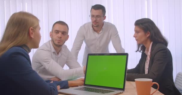 Retrato de quatro colegas reunidos no escritório dentro de casa. Pessoas de negócios usando o laptop com tela de tecla chroma verde e ter uma discussão — Vídeo de Stock