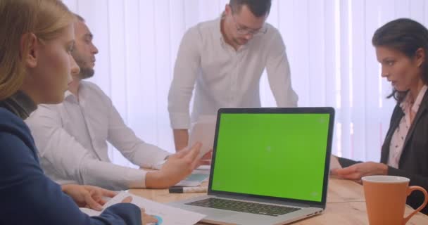 Portret czterech spotkań colllig w biurze w pomieszczeniu. Ludzie biznesowi używając laptopa z zielonym ekranem chrominancji i dyskusji na miejscu pracy — Wideo stockowe