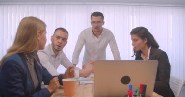 Ofis kapalı dört collleagues toplantı portresi. İş adamları dizüstü bilgisayar kullanarak ve işyerinde bir konuşma yapıyor
