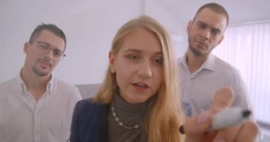 Ofiste kapalı alanda birlikte çalışan üç collleague'in portresi. Başarılı iş kadını iki erkek gözlem yaparken ekranda fikir beyin fırtınası