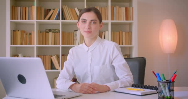 Primo piano ritratto di giovane donna d'affari caucasica attraente guardando la fotocamera sorridente felicemente seduto davanti al computer portatile in ufficio al chiuso — Video Stock