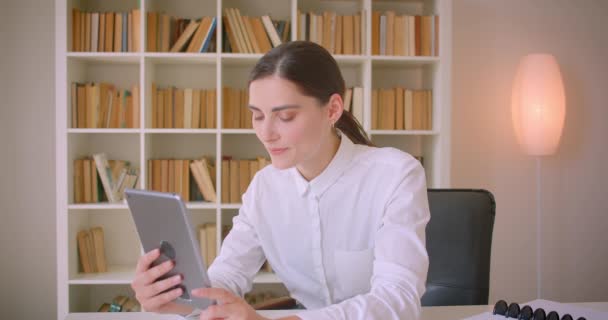 Zbliżenie Portret młodej atrakcyjnej kaukaski biznesmen o rozmowę wideo na tablecie machając Hi i rozmawiać wesonowo w biurze — Wideo stockowe