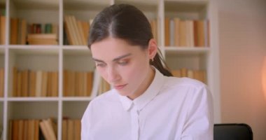 Arka planda kitaplıklar ile ofiste tablet üzerinde yazarak genç çekici kafkas iş kadını Closeup portre