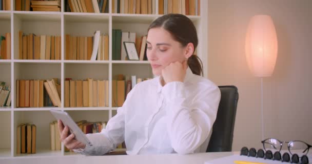 Nahaufnahme Porträt einer jungen attraktiven kaukasischen Geschäftsfrau, die das Tablet benutzt und im Büro glücklich lacht — Stockvideo
