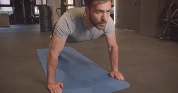 Closeup portrait of adult muscular athletic caucasian man making push ups in the gym indoors — Stock Video