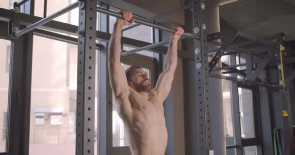 Closeup portrait of adult attractive caucasian man pulling up on bars in the gym indoors — Stock Video