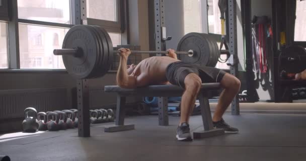 Retrato de primer plano del hombre caucásico musculoso sin camisa que levanta pesas que sentarse y descansar en el gimnasio en el interior — Vídeos de Stock