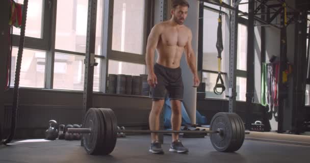 Primer plano retrato de hombre caucásico musculoso sin camisa levantando pesas motivado de pie en el gimnasio en el interior — Vídeo de stock