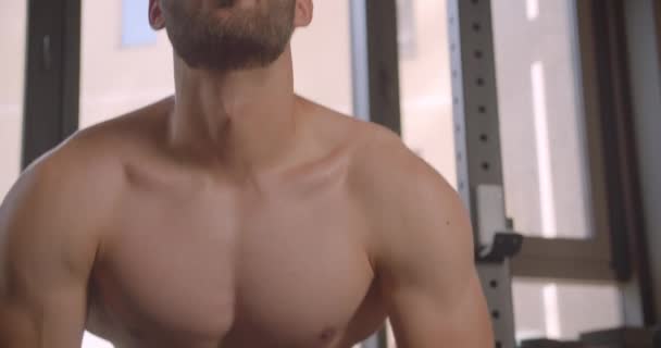 Kapalı spor salonunda gömleksiz kas beyaz erkek kol kaldırma ağırlıkları Closeup portre — Stok video