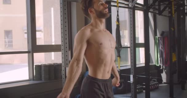 Close-up zijaanzicht portret van volwassen shirtless gespierde blanke man springen op het touw trainen in de sportschool binnenshuis — Stockvideo