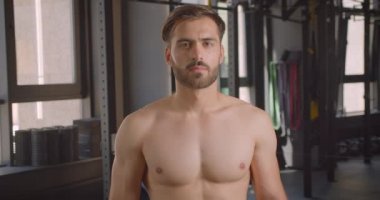 Gömleksiz yakışıklı beyaz adamın kapalı salonda spor salonunda duran motivasyonu ile kameraya bakan closeup portresi