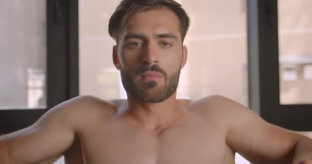 Nahaufnahme Porträt eines hemdlosen muskulösen kaukasischen Mannes, der in der Turnhalle unter Anstrengung Gewichte hebt — Stockvideo