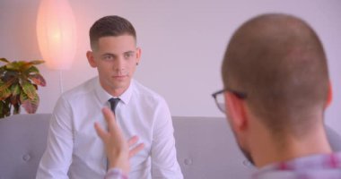 İki beyaz işadamının ofiste kapalı mekanda bir toplantı tartışması yaptığı yakın çekim portresi. Genç adam rahatsız ve kızgın oluyor