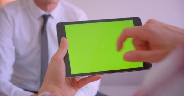 Retrato de primer plano del hombre de negocios hablando con su compañero tableta con pantalla de croma verde en la oficina — Vídeo de stock