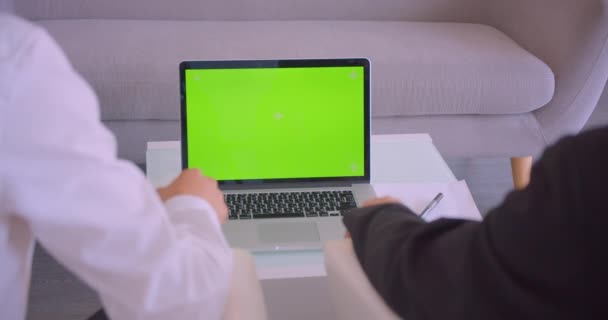 Close-up achteraanzicht portret van twee zakenlui met behulp van laptop met groen scherm en schud handen overeenkomst in het kantoor binnenshuis — Stockvideo