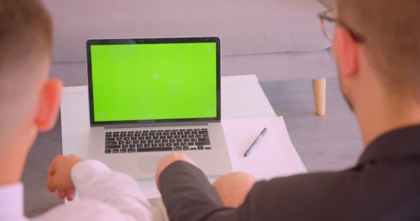 Closeup pohled na portrét dvou úspěšných podnikatelů s použitím notebooku se zelenou obrazovkou v kanceláři v interiérech — Stock video