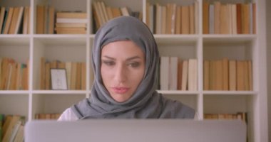 Türbanlı genç çekici Müslüman iş kadınının kapalı kütüphanede kahve içerken görüntülü araması olan closeup portresi