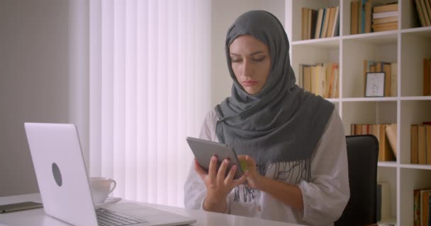 Κοντινό πλάνο του νεαρού ελκυστική μουσουλμανική επιχειρηματίας σε χιτζάμπ χρησιμοποιώντας tablet και δείχνοντας πράσινη οθόνη στην κάμερα στο γραφείο σε εσωτερικούς χώρους — Αρχείο Βίντεο