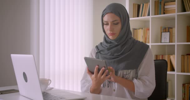 Κοντινό πλάνο του νεαρού ελκυστική μουσουλμανική επιχειρηματίας σε χιτζάμπ χρησιμοποιώντας tablet και δείχνοντας πράσινη οθόνη αποχρώσεων στην κάμερα στο γραφείο σε εσωτερικούς χώρους — Αρχείο Βίντεο