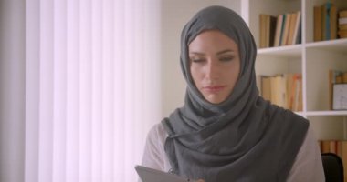 Tablet kullanarak ve ofis kapalı kameraya yeşil renk anahtar ekranı gösteren hijab genç Müslüman iş kadını Closeup portre