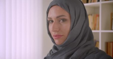 Türbanlı genç başarılı Müslüman iş kadınının kapalı ofiste neşeyle gülümseyen kameraya bakan closeup portresi