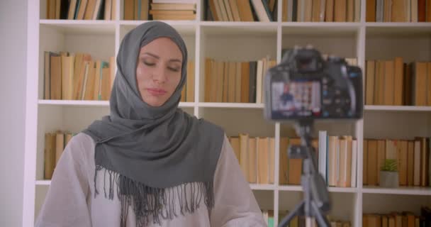 Close-up portret van jonge aantrekkelijke moslim blogger in hijab praten over camera binnenshuis — Stockvideo