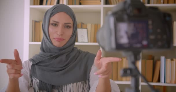 Крупним планом портрет молодого привабливого мусульманського блогера в хіджабі, який говорить про жест камери в приміщенні — стокове відео