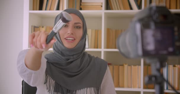 Potret tertutup muda menarik muslim kecantikan blogger dalam jilbab berbicara pada kamera membuat review produk di dalam ruangan — Stok Video