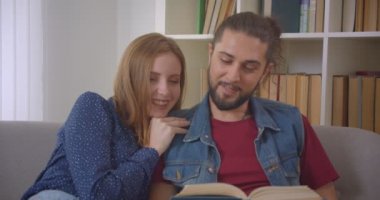 Genç beyaz erkek arkadaşı ve kız arkadaşı evde sevinçle kitap okuma kanepede oturan portre çekimi.