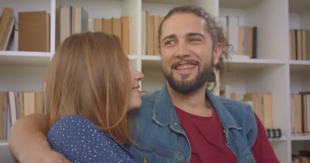 젊은 백인 남자 친구와 여자 친구가 소파에 앉아 집에서 즐겁게 웃고있는 초상화 샷. — 비디오