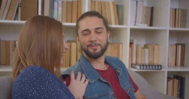 Kanepede kitap okuma oturan ve evde sevinçle tartışıyor genç hipster çift portre çekim.