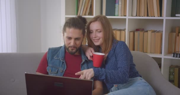 Hipster cara e sua namorada usa computador portátil falando em videochat on-line em casa . — Vídeo de Stock