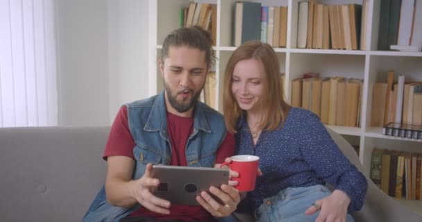 Hipster jeune couple jouant jeu sur tablette étant absorbé et intéressé à la maison . — Video