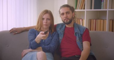 Hipster genç çift Tv'de komedi filmi izlerken ve evde neşeyle konuşuyor.