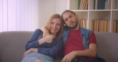 Hipster genç çift Tv'de komedi filmi izlerken ve evde neşeyle gülüyor.