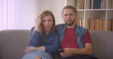 Hipster genç çift Tv'de korku filmi izlerken ve evde korkmuş ama neşeli olmak.