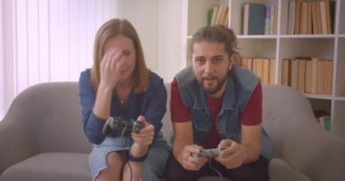Hipster genç çift emilir ve evde ilgi joysticks kullanarak video oyunu oynar.