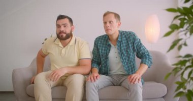 Tv'de futbol izleyen iki beyaz adamın yakın çekim portresi evde ki kanepede oturarak duygusal olarak