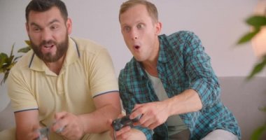 Evde kanepede oturarak birlikte video oyunu oynayan iki kafkas heyecanlı adamın closeup portresi